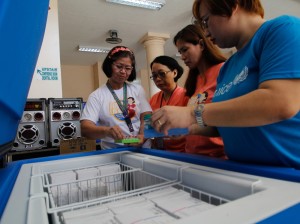 A Unicef staff member inspects vaccines with volunteer health workers at a government health center in Happyland, a slum area in Manila. UNICEF PHOTO