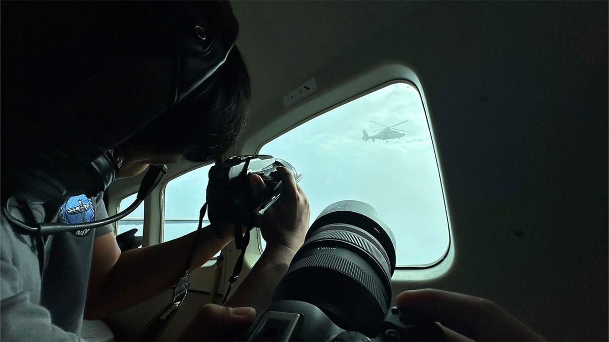 CHALLENGE, DEFIANCE Journalists onboard the plane of the Bureau of Fisheries and Aquatic Resources take photos of a Chinese helicopter that came alarmingly close in the airspace over Panatag (Scarborough) Shoal in the West Philippine Sea on Tuesday. —AP