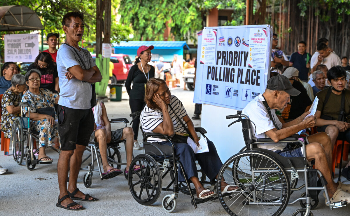 Wheelchair-bound voters wait in line at a polling station's priority section during mid-term elections in Manila on May 12, 2025.
