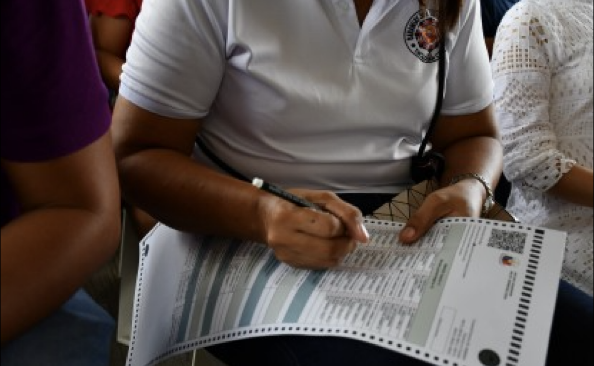 A woman filling up a sample ballot.