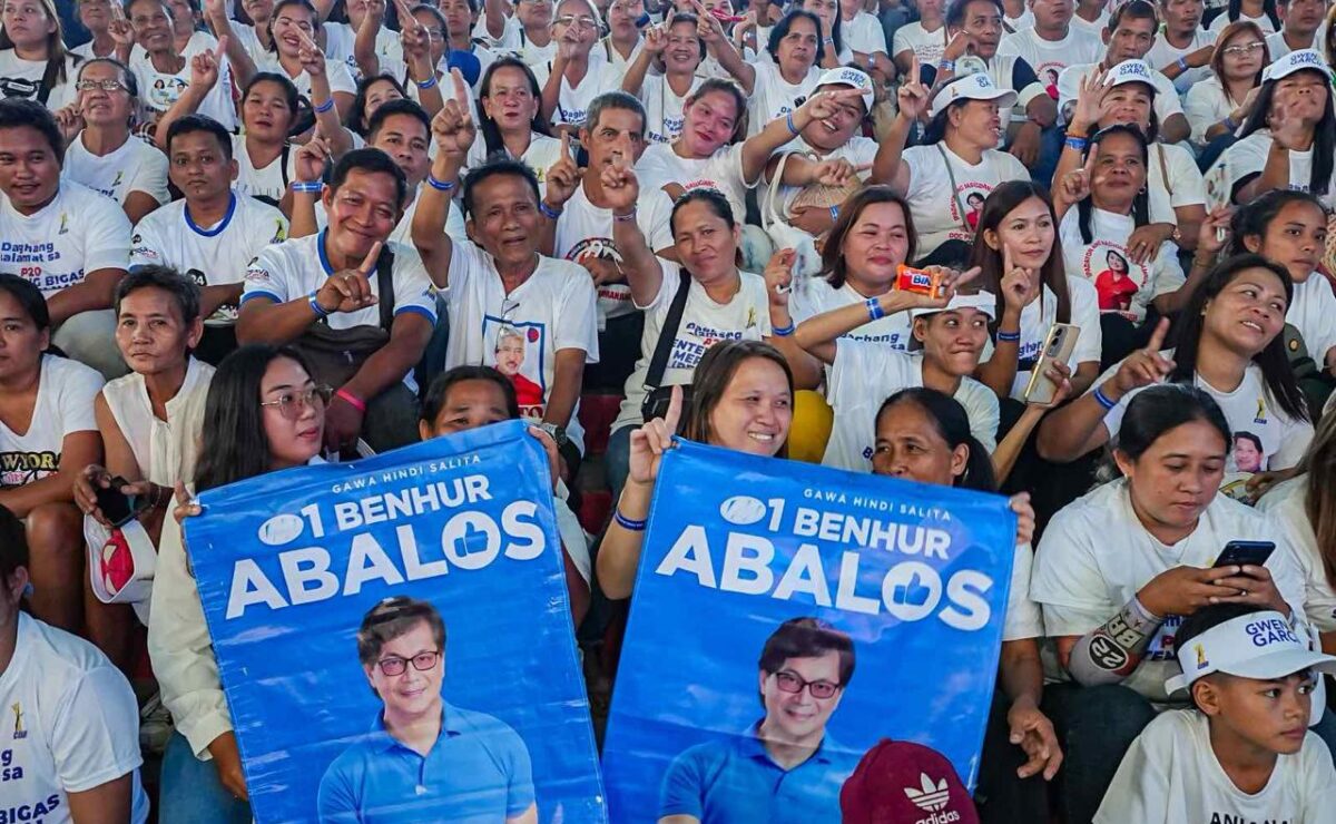 Supporters hold posters as they listen to Benhur Abalos at Cebu rally